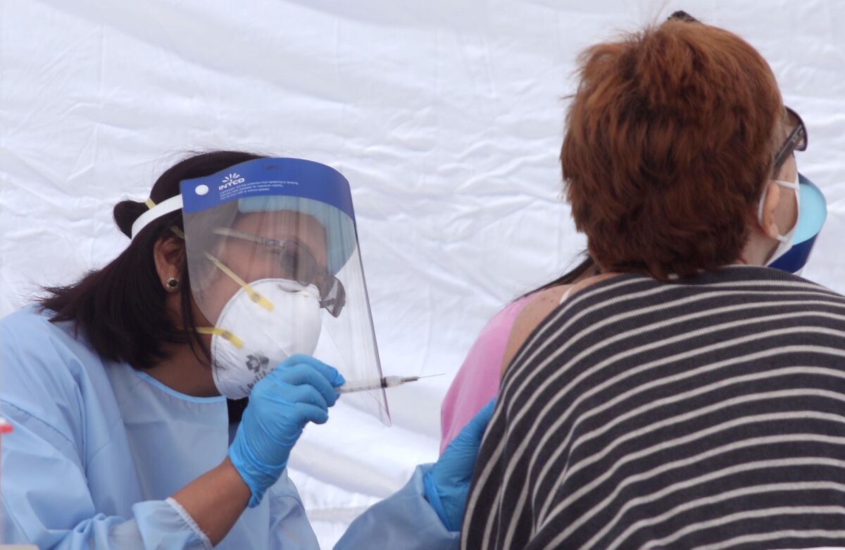 A nurse gives a woman a COVID-19 vaccine