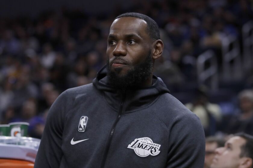 Los Angeles Lakers' LeBron James watches from the bench during the first half of the team's preseason NBA basketball game against the Golden State Warriors on Friday, Oct. 18, 2019, in San Francisco. (AP Photo/Ben Margot)
