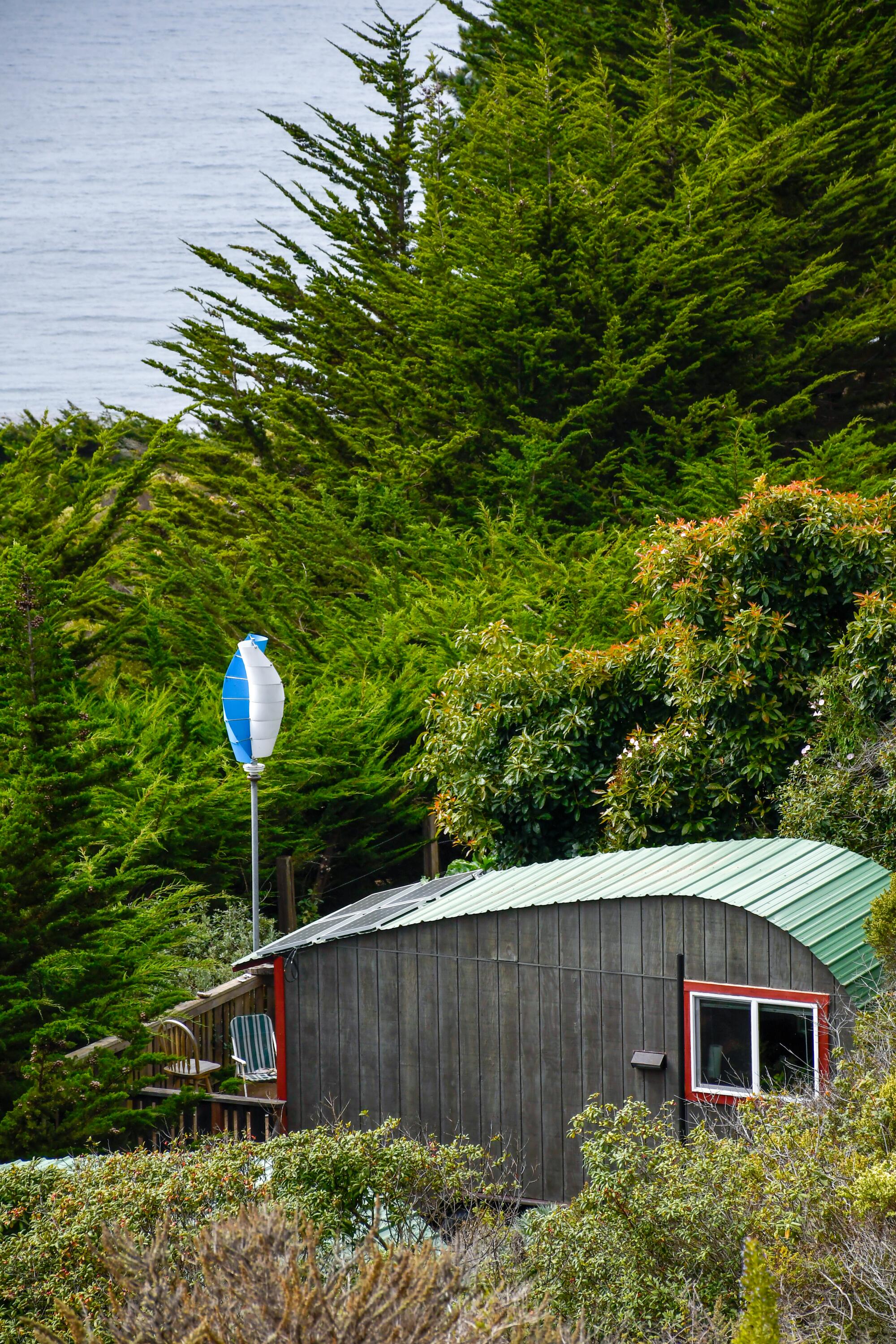 A small cabin-like structure nearly hidden amidst greenery, with the ocean in the background.