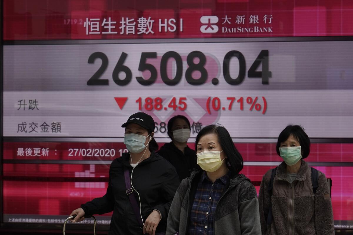 People walk past an electronic board showing Hong Kong's share index Thursday in Hong Kong.