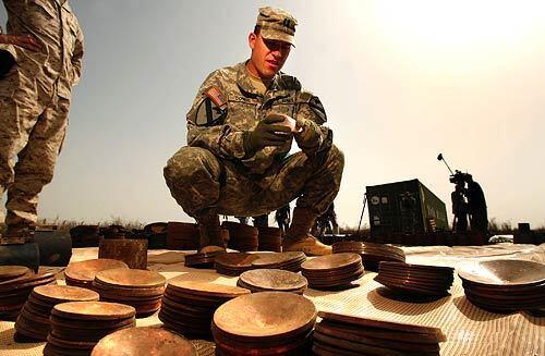 U.S. Army Captain Clay Combs examines a copper plate, one of 150 found recently in a Diyala Province weapons cache that has been used recently in the production of extremely destructive EFP's, explosively formed projectiles. These powerful roadside bombs were found alongside mortar rounds, 122mm rockets and RPG launchers.