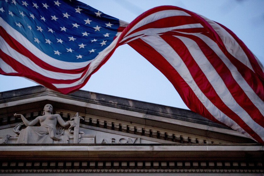 FILE - In this March 22, 2019 file photo, an American flag flies outside the Department of Justice in Washington. The Department of Justice says in a statement that hackers have been attempting to obtain intellectual property and public health data related to vaccines, treatments, and testing. (AP Photo/Andrew Harnik)