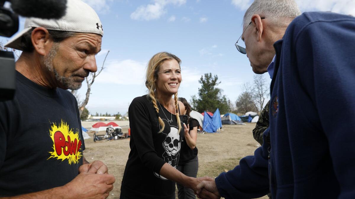 U.S. District Judge David Carter, right, greets homeless residents Frank Fabozzi, 56, and Amy Potter, 47, while surveying the homeless encampment along the Santa Ana River in Anaheim in February.