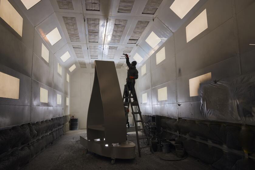 A worker applies paint to a section of a decommissioned wind turbine blade at the Canvus manufacturing facility in Avon, Ohio, US, on Wednesday, Oct. 25, 2023. To keep turbine blades from piling up in landfills, startups like Canvus are turning them into new products and free marketing for wind power. Photographer: Brian Kaiser/Bloomberg via Getty Images