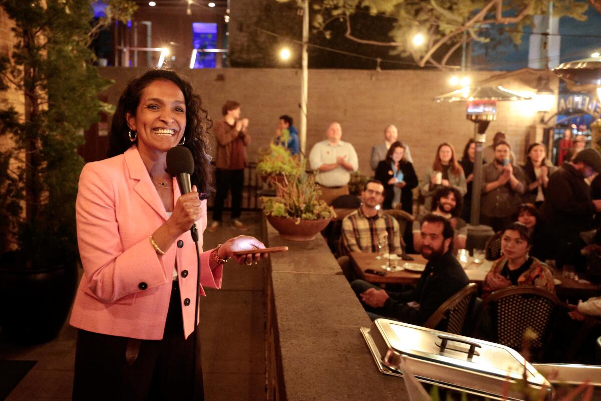  Councilmember Nithya Raman smiles as she speaks to an outdoor crowd at night.