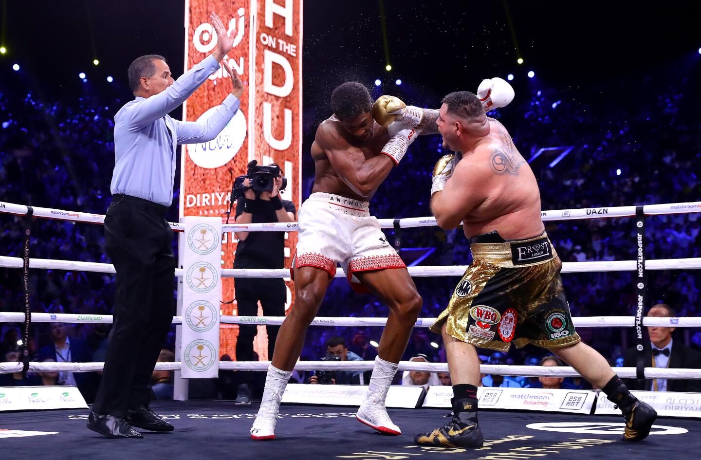 Andy Ruiz Jr. and Anthony Joshua trade punches as referee Luis Pabon gestures during a heavyweight tile fight on Dec. 7 in Diriyah, Saudi Arabia.