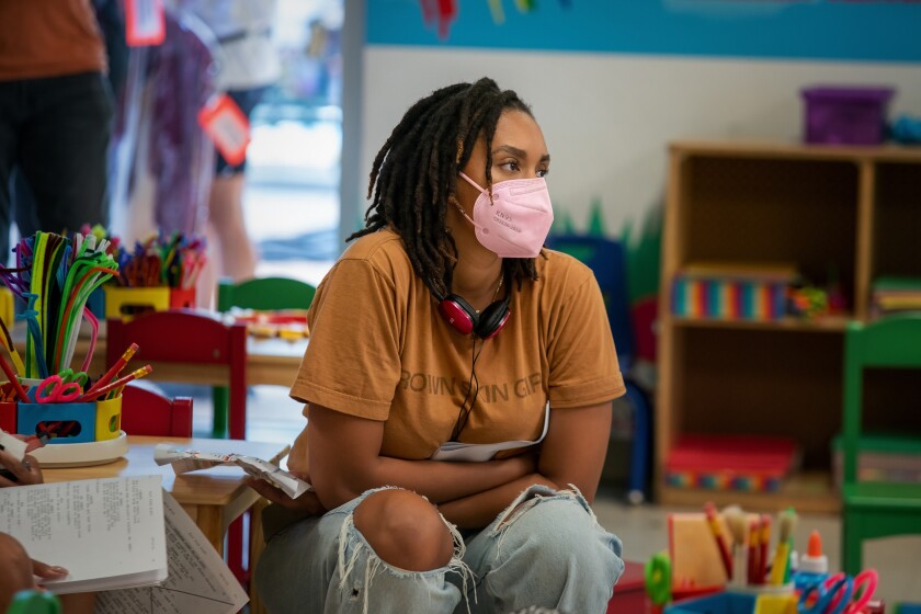 A woman in a pink mask sitting amid a TV set