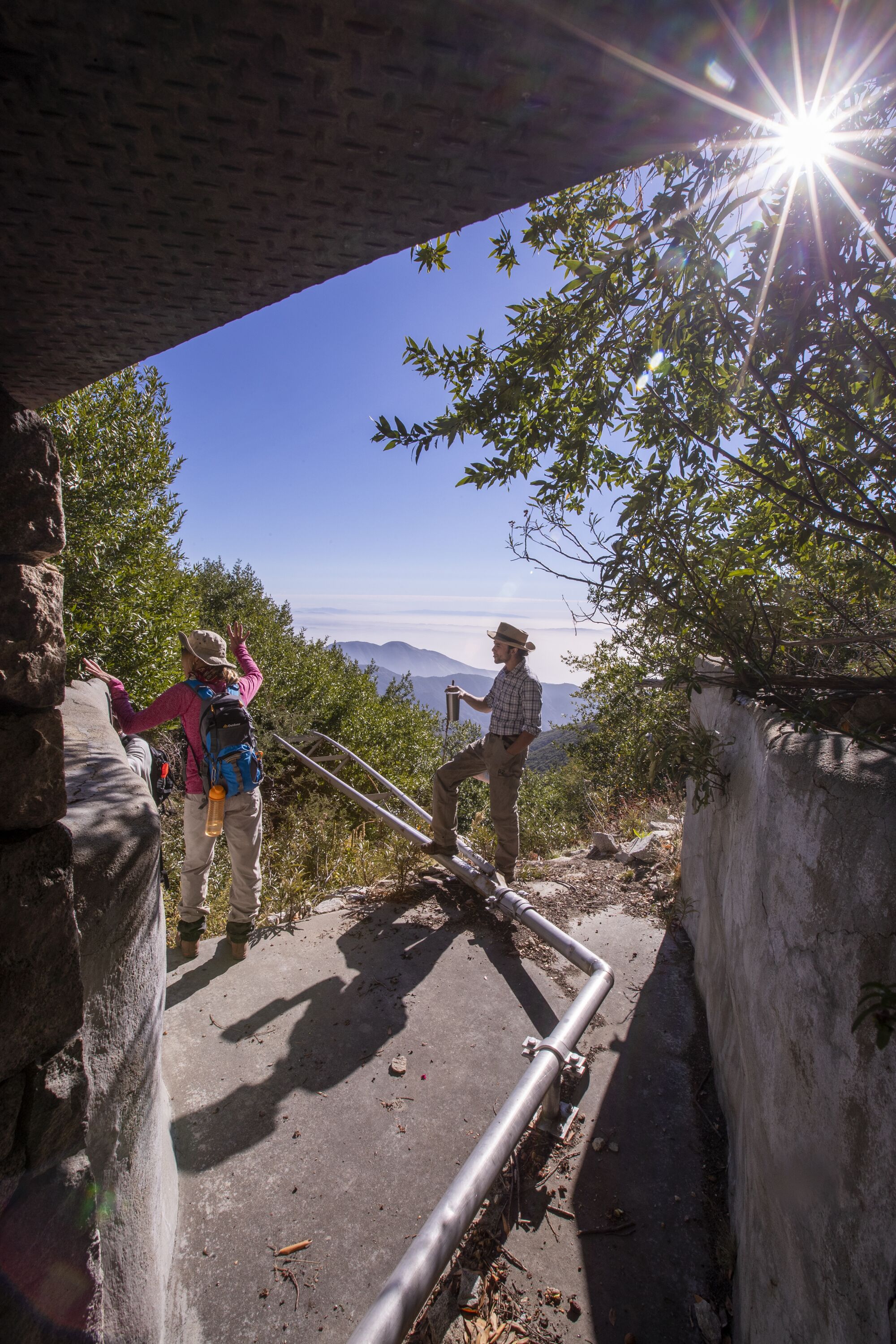 Hikers survey the landscape next to a steel pipe