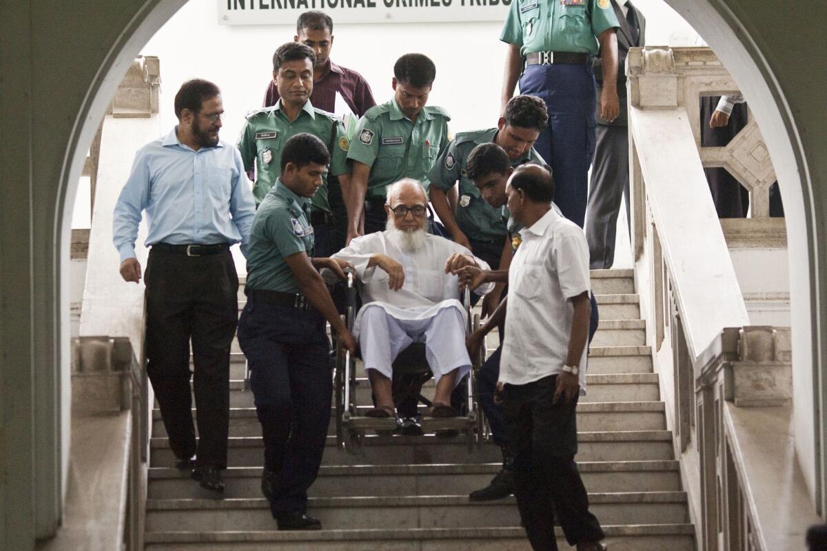 Ghulam Azam, the former chief of Bangladesh's Jamaat-e-Islami party, is assisted by security personnel at the Bangladesh International Crimes Tribunal in Dhaka on May 13, 2012.