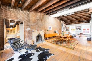 The pre-war penthouse mixes old and new with exposed brick and rustic beams broken up by five skylights.