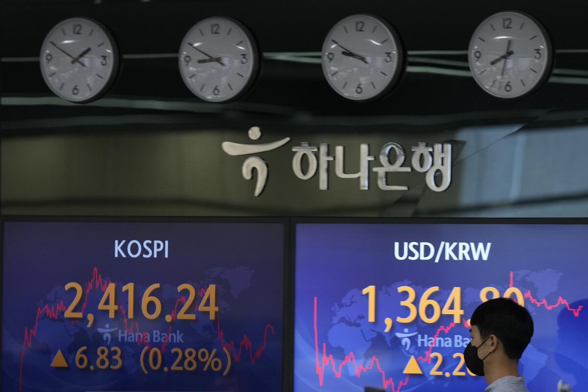 A currency trader walks by the screens showing the Korea Composite Stock Price Index (KOSPI), left, and the foreign exchange rate between U.S. dollar and South Korean won at a foreign exchange dealing room in Seoul, South Korea, Monday, Sept. 5, 2022. Asian stock markets declined Monday after Wall Street ended last week lower and China tightened anti-virus controls. (AP Photo/Lee Jin-man)