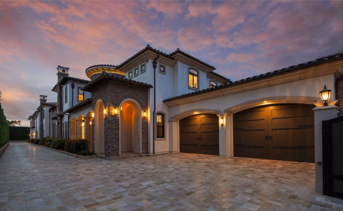 An exterior view of a home shows a double garage, a stone covered entryway and the two-story mansion.