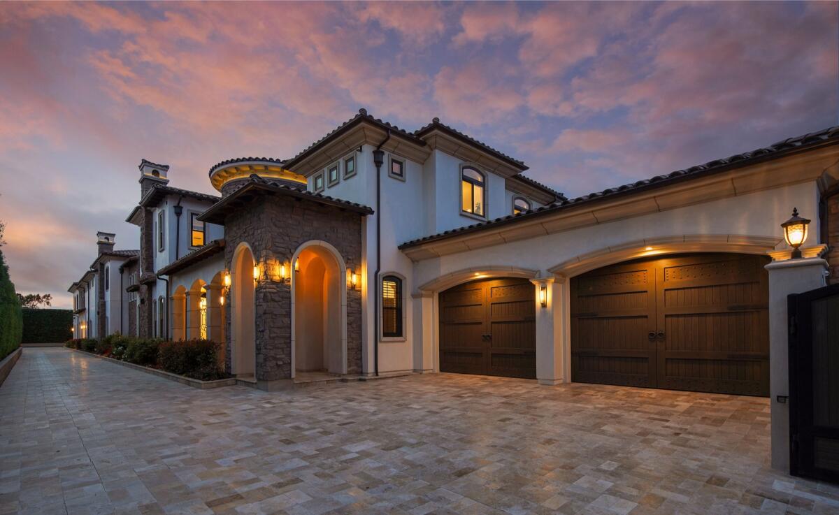 An exterior view of a home shows a double garage, a stone covered entryway and the two-story mansion.