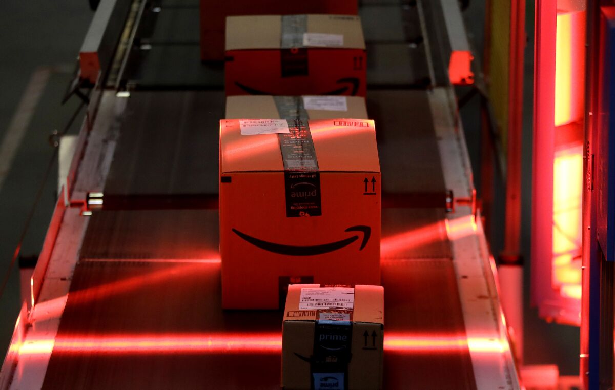 FILE - Packages riding on a belt are scanned to be loaded onto delivery trucks at the Amazon Fulfillment center in Robbinsville Township, N.J., on Aug. 1, 2017. Federal work-safety investigators are looking into the death of an Amazon worker and an injury that potentially led to the death of another employee, adding to a probe already underway following a third fatality during the company's annual Prime Day shopping event in mid-July, 2022. (AP Photo/Julio Cortez, File)