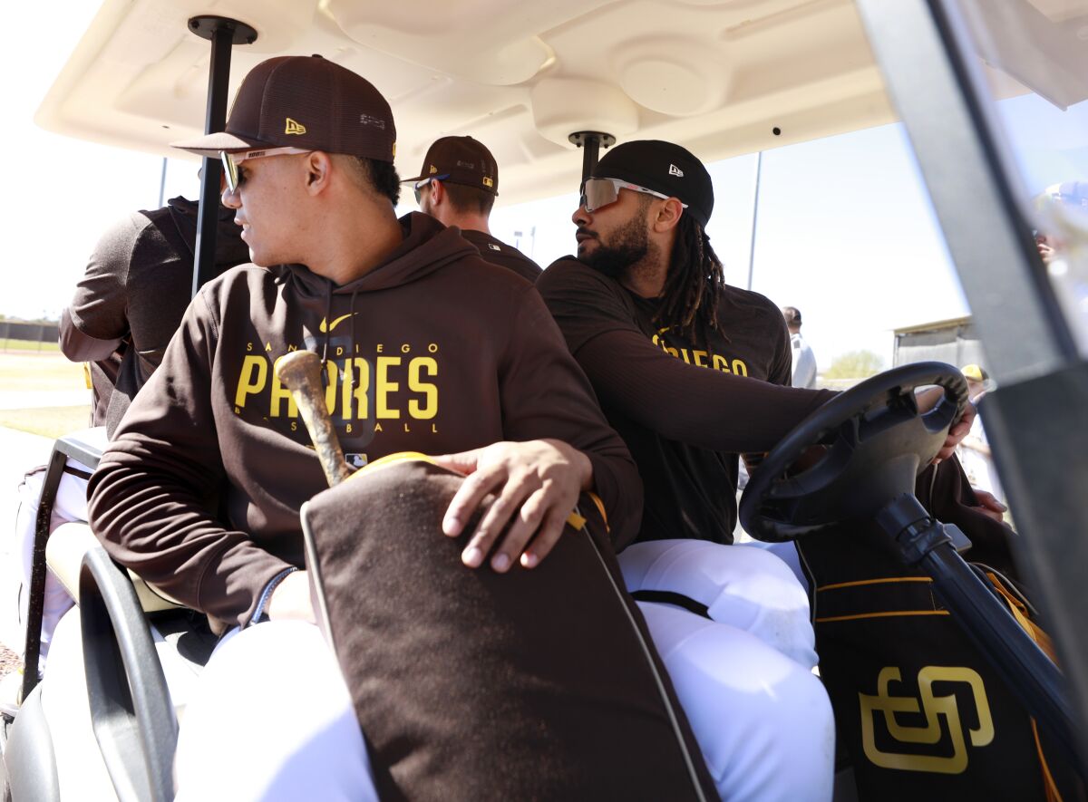 The Padres' Juan Soto looks back as Fernando Tatis Jr. drives a golf cart 