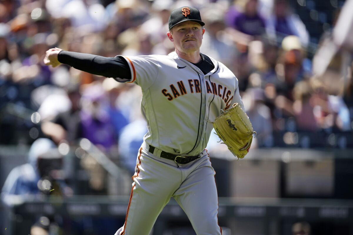 San Francisco Giants starting pitcher Logan Webb throws to first base to force out Colorado Rockies' Yonathan Daza to end the fifth inning of a baseball game Wednesday, May 18, 2022, in Denver. (AP Photo/David Zalubowski)