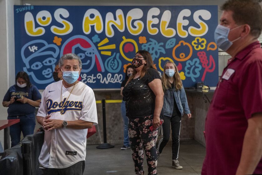 LOS ANGELES, CA - MAY 14, 2021: Guilmar Nuyens, foreground, left, of West Covina, waits with others in line to order food from China Cafe inside the Grand Central Market on Broadway in downtown Los Angeles. The CDC says people fully vaccinated against COVID-19 do not need to wear masks indoors or outdoors in most situations but California hasn't relaxed its rules just yet. (Mel Melcon / Los Angeles Times)