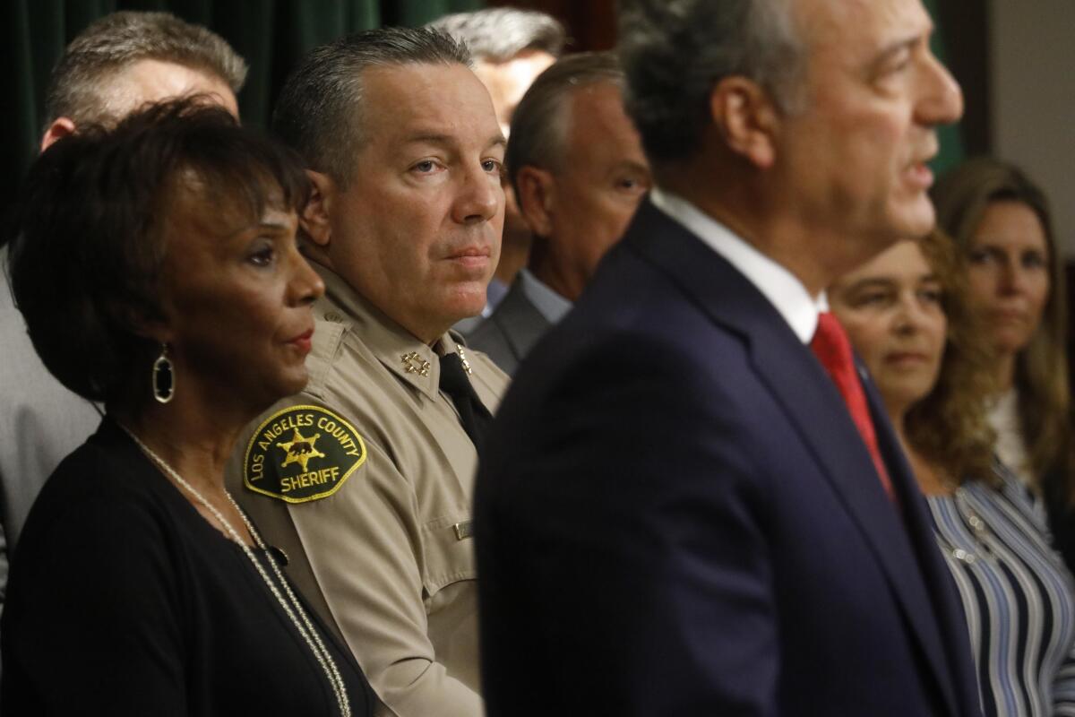 The sheriff and other officials stand behind the U.S. attorney in Los Angeles at a news conference