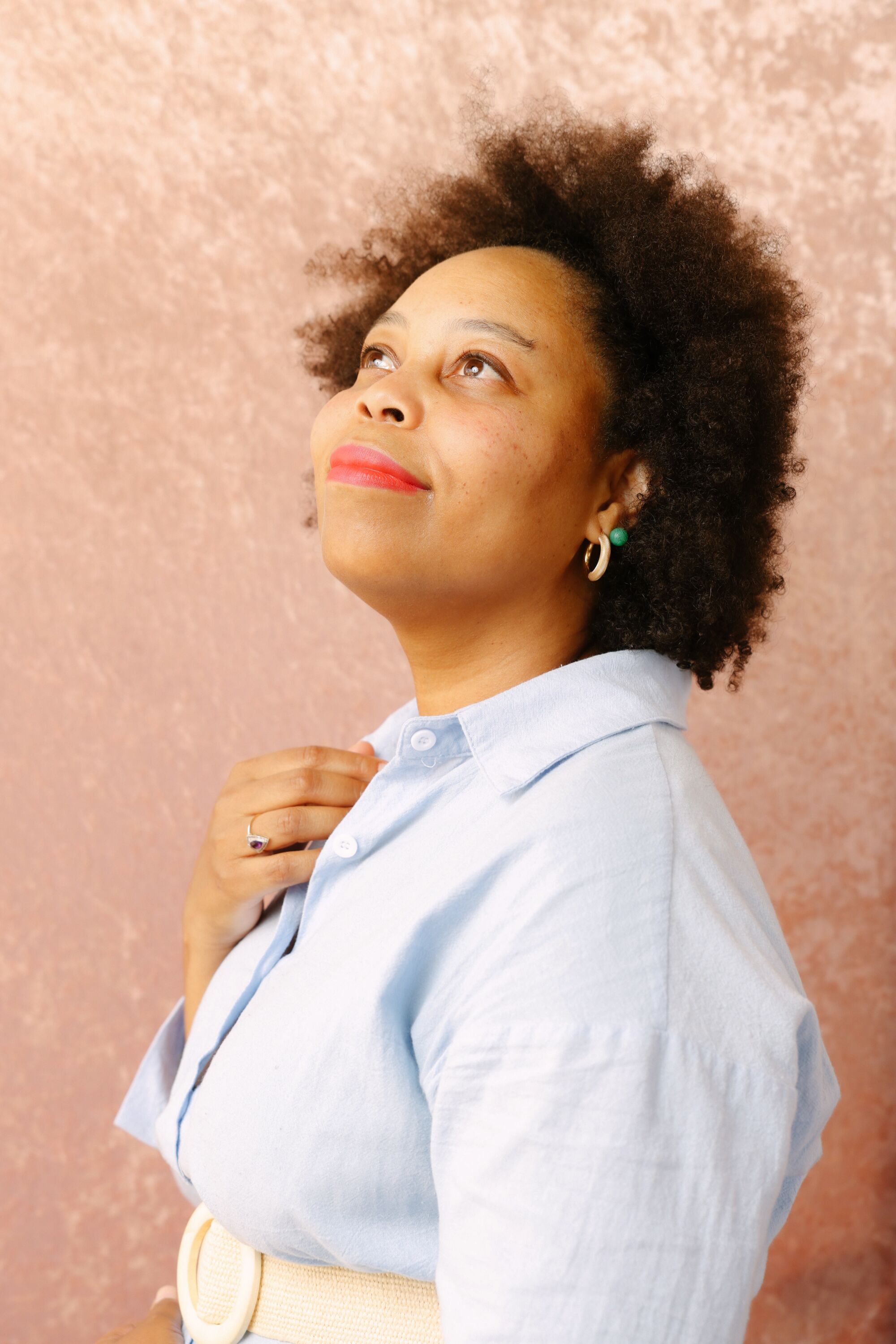 A woman in a blue blouse smiles and looks skyward.