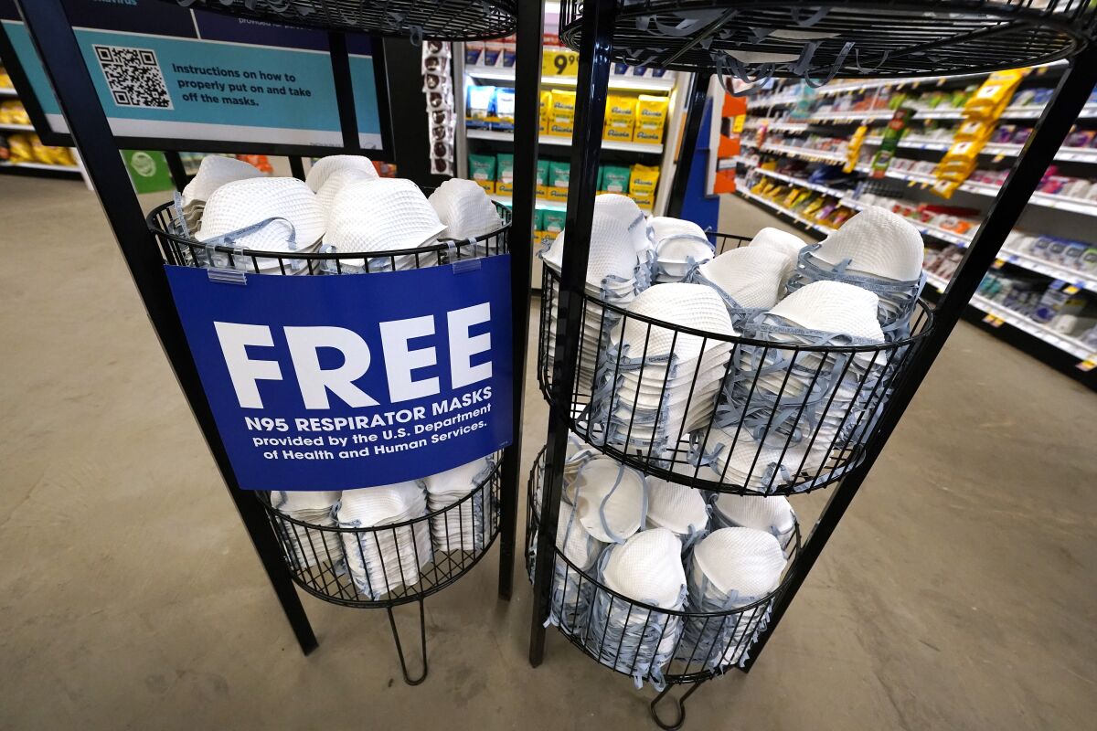 Free N95 respirator masks are piled in in a metal bin at a grocery store.