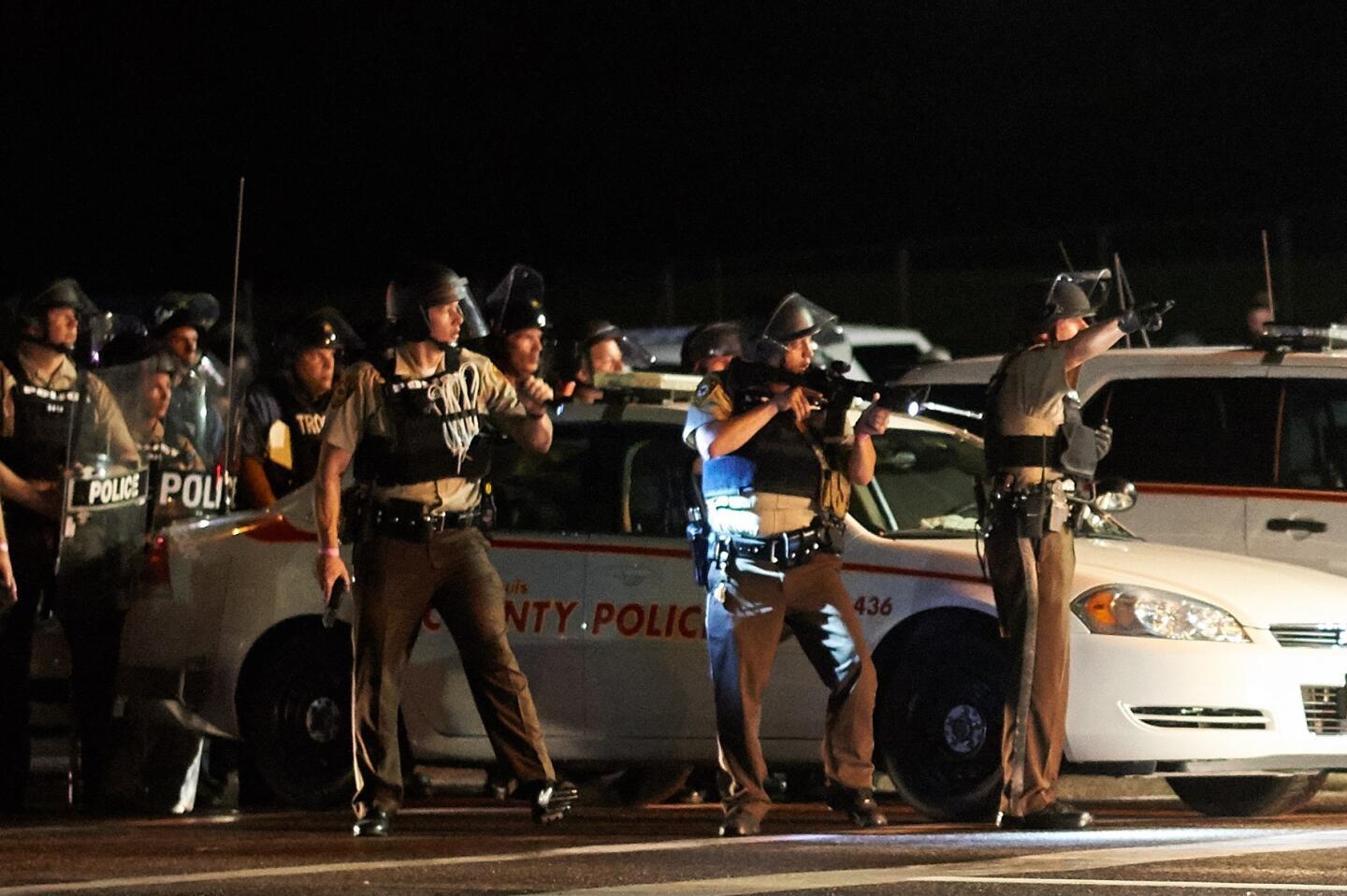A St. Louis County police officer directs an oncoming car looking to evacuate the area after a police involved shooting during a protest march on August 9, 2015 on West Florissant Avenue in Ferguson, Missouri.