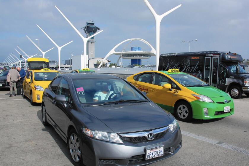 A car with Uber and Lyft decals leaves the departure terminal at Los Angeles International Airport.