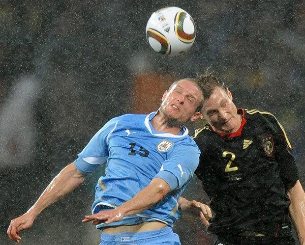 Uruguay's midfielder Diego Perez and Germany's midfielder Marcell Jansen jump for the ball during the 2010 World Cup third place football match Uruguay vs. Germany on July 10, 2010 at Nelson Mandela Bay stadium in Port Elizabeth.