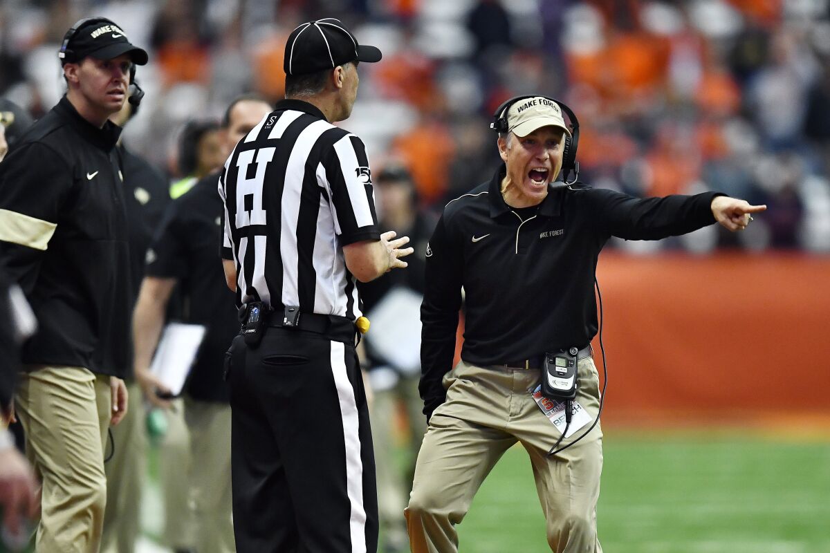 FILE - In this Saturday, Nov. 30, 2019, file photo, Wake Forest head coach Dave Clawson, right, speaks to an official during the second half of an NCAA college football game against Syracuse in Syracuse, N.Y. Wake Forest has been to four straight bowl games but will have to overcome significant personnel losses on offense in Clawson's seventh season. (AP Photo/Adrian Kraus, File)