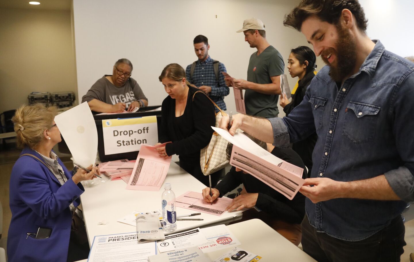 Election official Zahra Katimi, left, answers questions about filling out provisional ballots from voters as Matthew Tetreault, right, looks over his ballot before turning it in at the polling place at Santa Monica Place Mall.