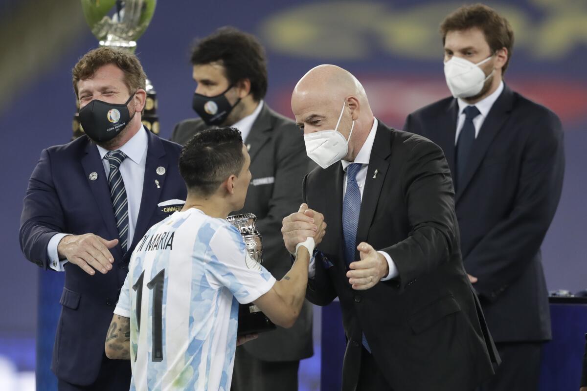 FIFA President Gianni Infantino, right, greets Argentina's Angel Di Maria at the award ceremony after his team won 1-0 against Brazil in the Copa America final soccer match at the Maracana stadium in Rio de Janeiro, Brazil, Saturday, July 10, 2021. (AP Photo/Andre Penner)