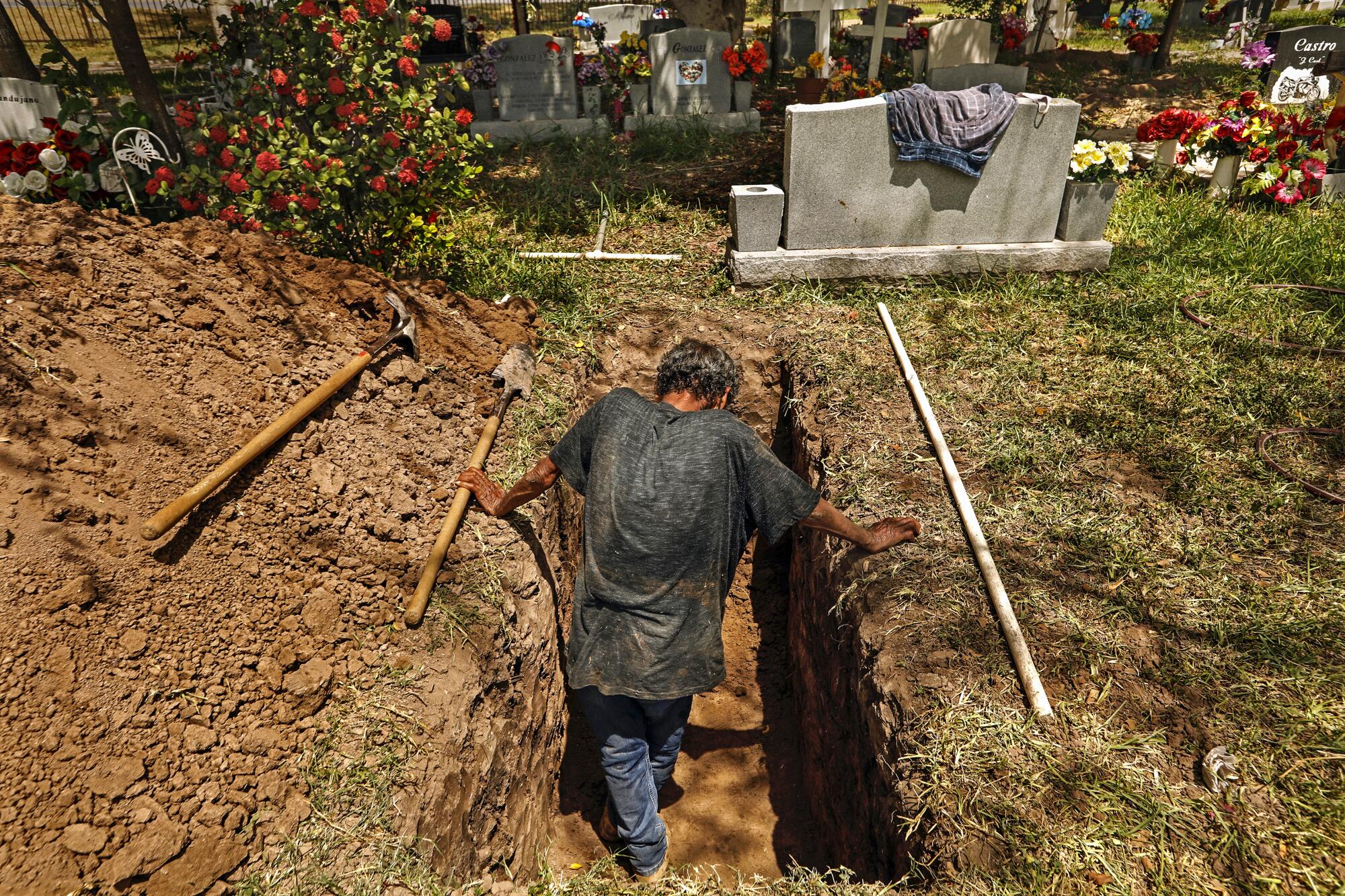 Jesus Torres, 75, digs graves with a shovel at La Piedad Cemetery in McAllen, Texas.
