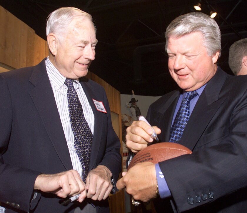 FILE - Former Dallas Cowboys coach Jimmy Johnson, right, autographs a football while chatting with Dave Campbell, Selection Committee chairman for the Texas Sports Hall of Fame, on Feb. 27, 2001, in Waco, Texas. Campbell, founder of the Texas Football preview magazine that became a fixture in this football-crazy state, has died Friday night, Dec. 10, 2021, at his home in Waco, said Greg Tepper, managing editor of Dave Campbell's Texas Football. He was 96. (Duane A. Laverty/Waco Tribune-Herald via AP, File)