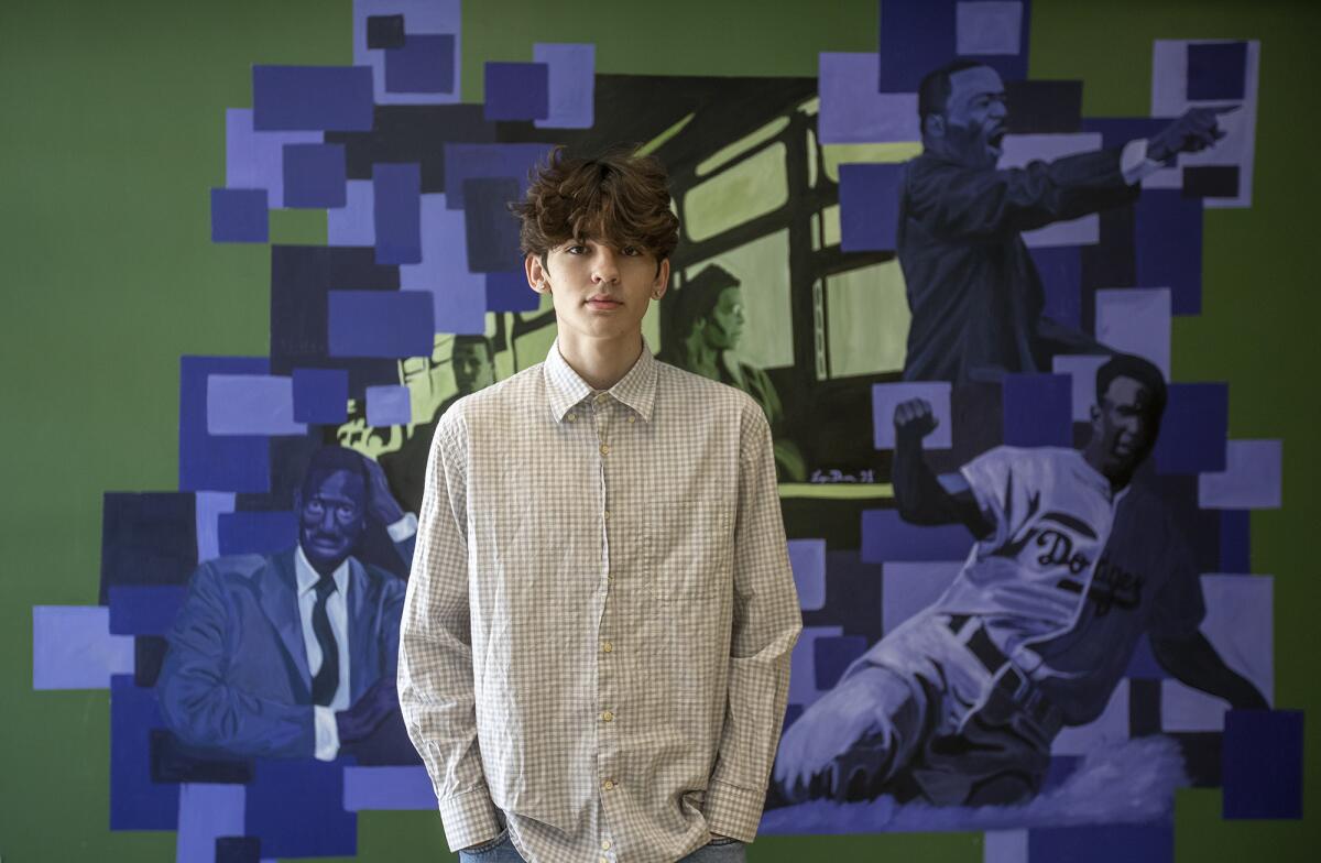 Logan Dunn, a recent graduate from Edison High School, stands by a civil rights mural that he completed at the school.