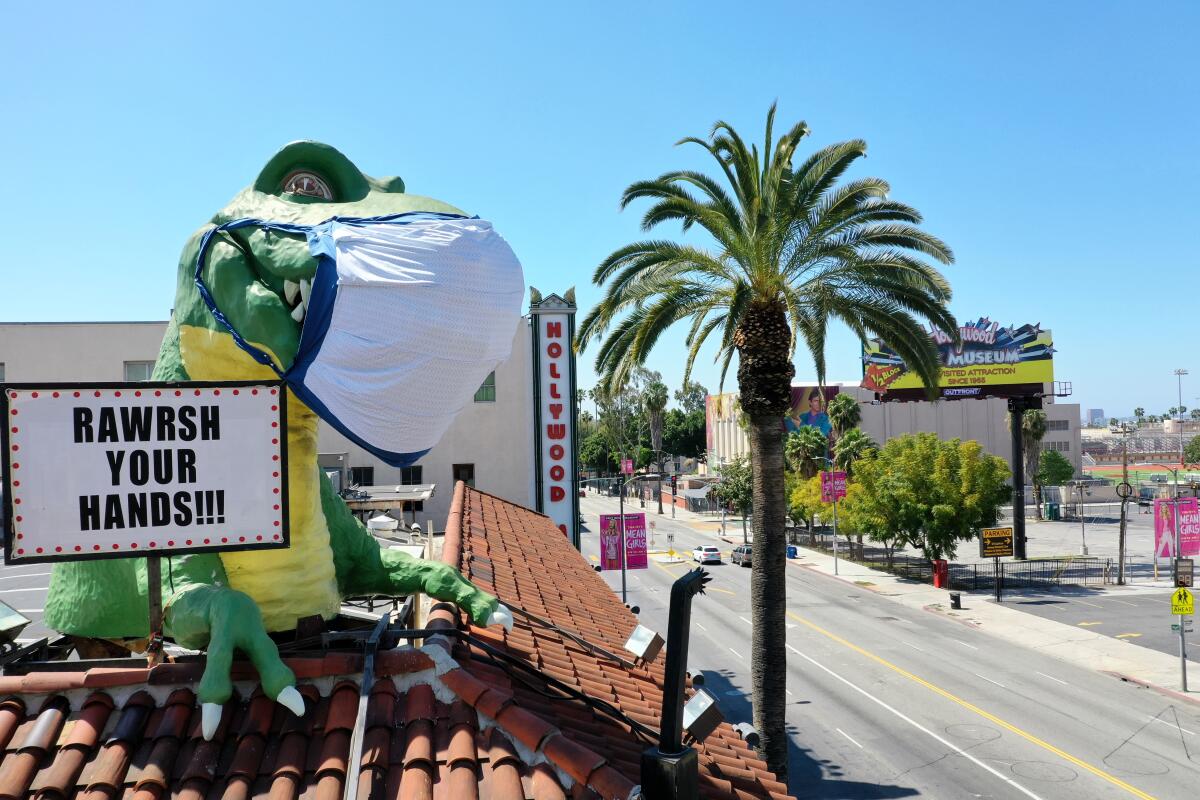 Un gigante T-Rex con una máscara protectora envía un mensaje de Coronavirus a una intersección casi vacía de Hollywood Blvd. y Highland Ave. desde lo alto de Ripley's Believe It or Not! Odditorium, que está temporalmente cerrado, en Hollywood, CA, el 21 de abril de 2020.