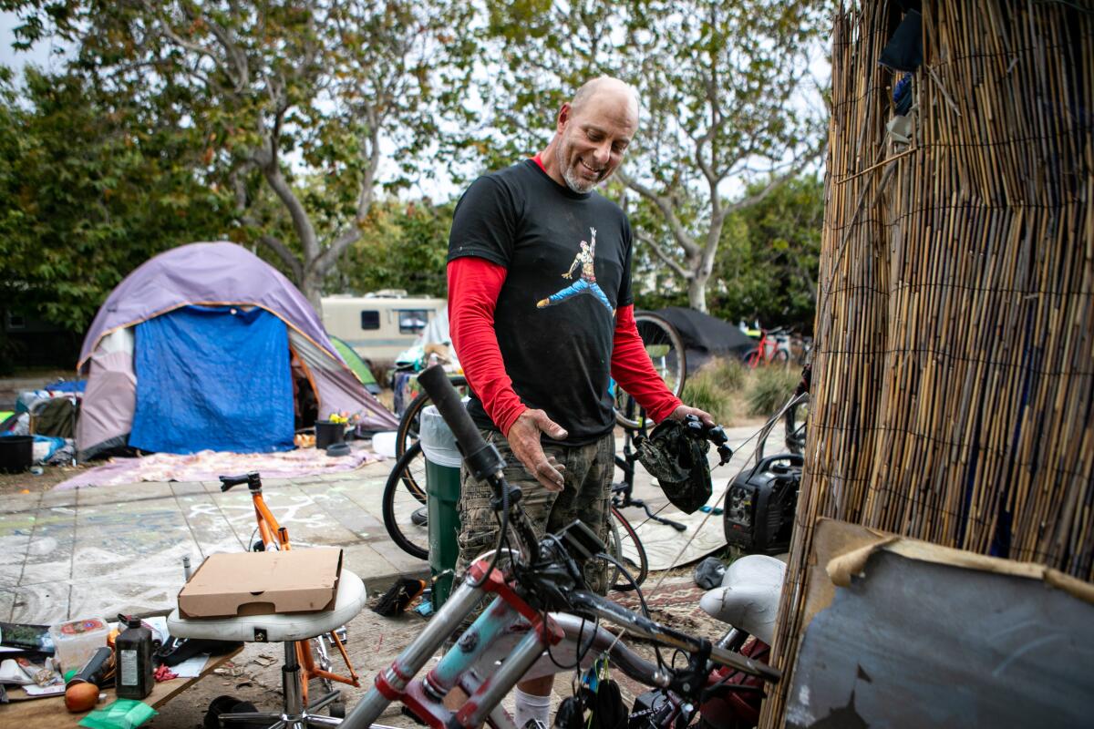 A man stands at his tent at a homeless encampment on May 23, 2022.