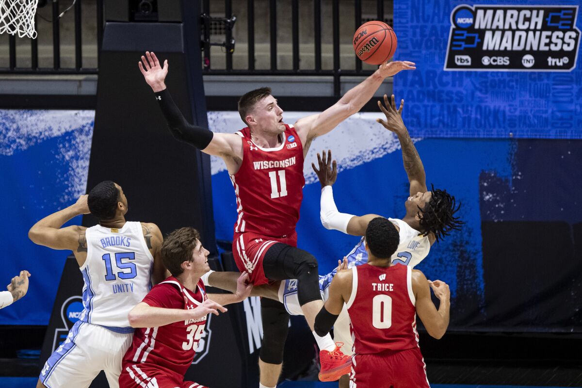 Wisconsin's Micah Potter, top, blocks a shot by North Carolina's Caleb Love during the first half Friday.