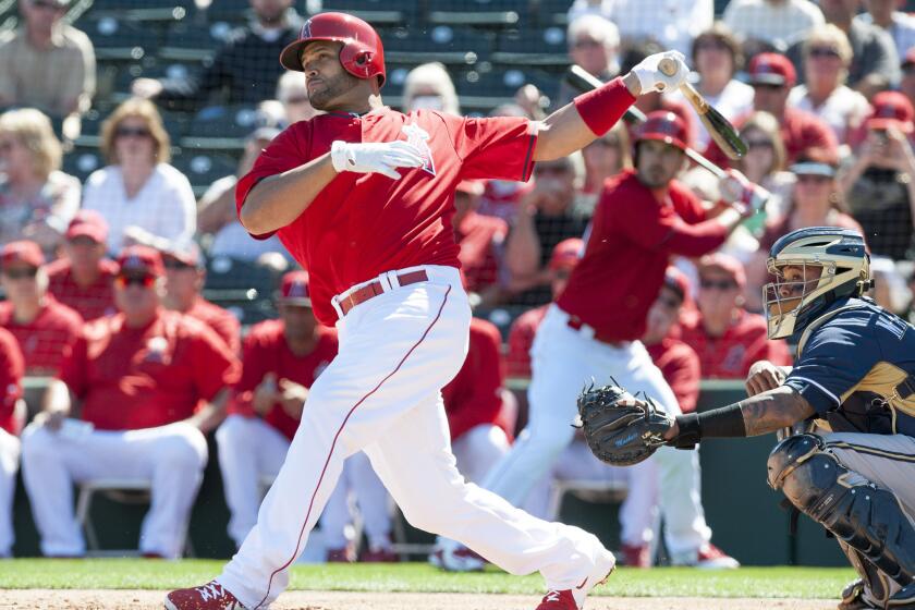 Angels first baseman Albert Pujols hits the ball against the Brewers during the Angels' spring training home opener.