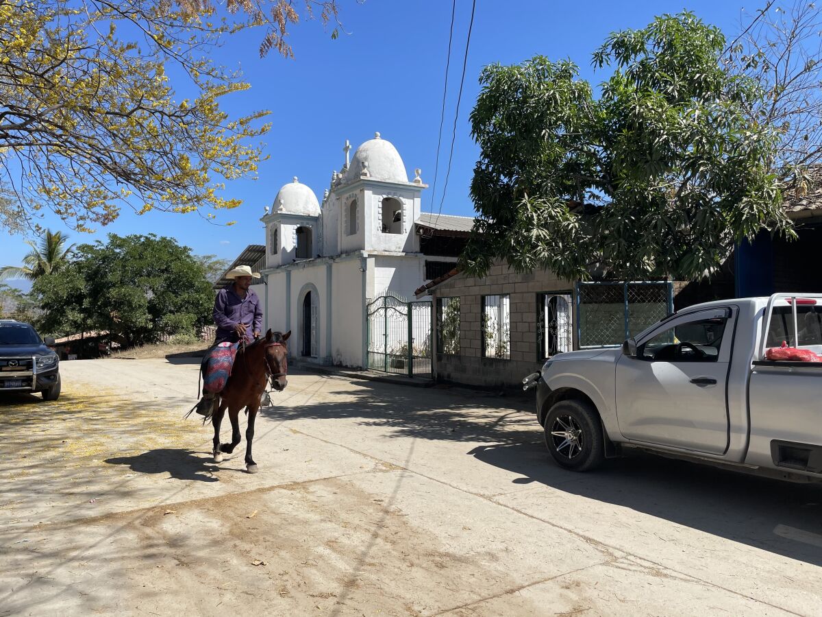 A rider on horseback traverses the dusty roads of San Pedro, El Salvador.