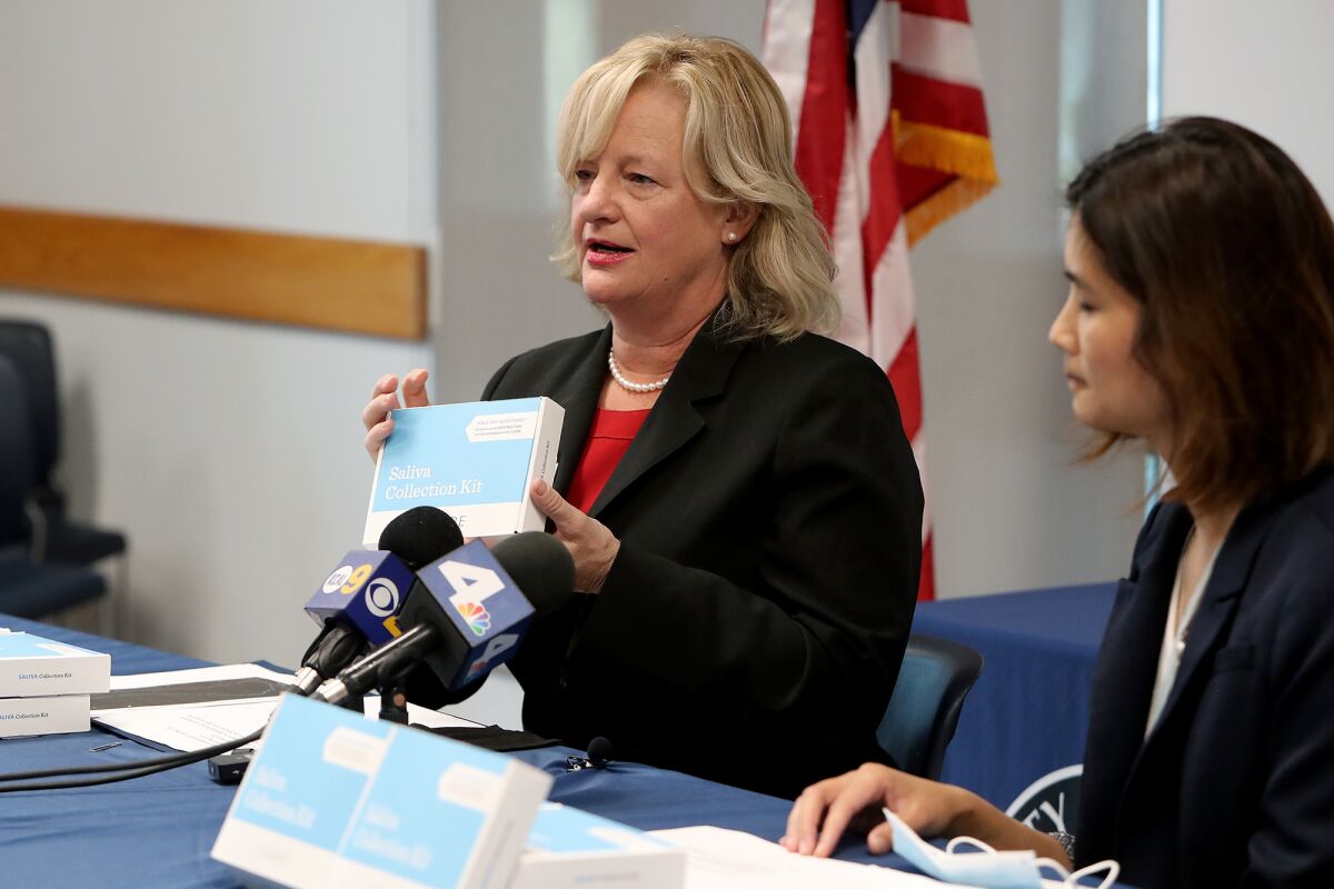 Orange County Supervisor Katrina Foley, left, speaks about a saliva collection kit with Dr. Regina Chinsio-Kwong.