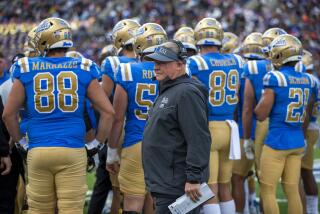UCLA coach Chip Kelly walks back to the sidelines during a time out in front of a group of Bruins players