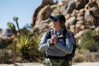 JOSHUA TREE NATIONAL PARK, CA - AUGUST 19, 2024: Preventative Search and Rescue Program Coordinator Anna Marini waits at the Hidden Valley trailhead to check on hikers during triple-digit temperatures on August 19, 2024 in Joshua Tree National Park, California. The PSAR program is a team of about 30 volunteers and some staffers who go out to trailheads on the park to make sure visitors are staying safe. (Gina Ferazzi / Los Angeles Times)