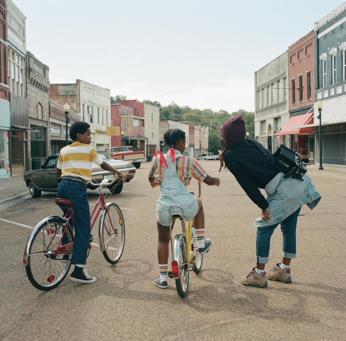 A woman directs two children on bicycles.