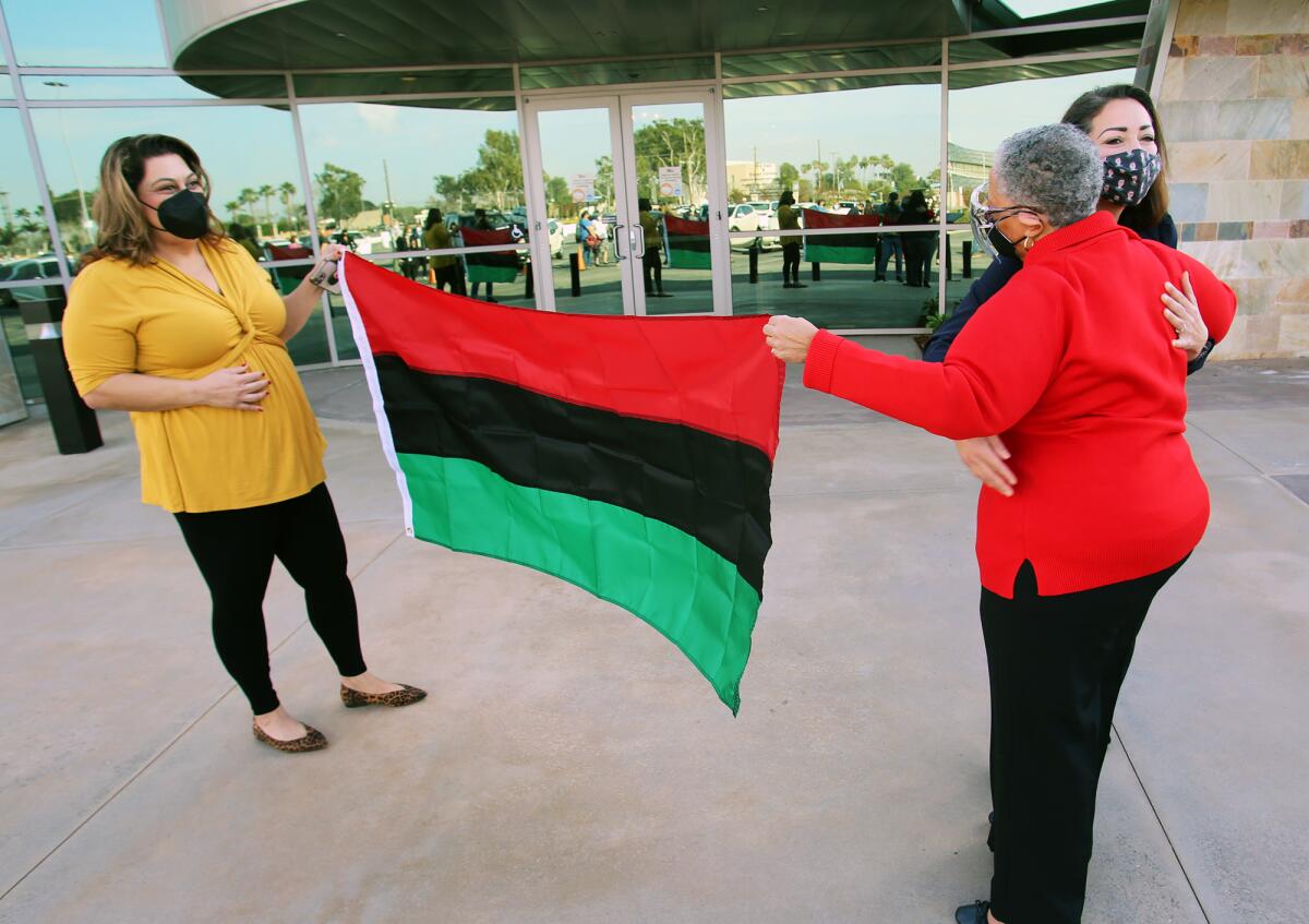Melahat Rafiei, left, and a colleague on the O.C. Fair Board, raise the Pan African flag to honor Black History Month