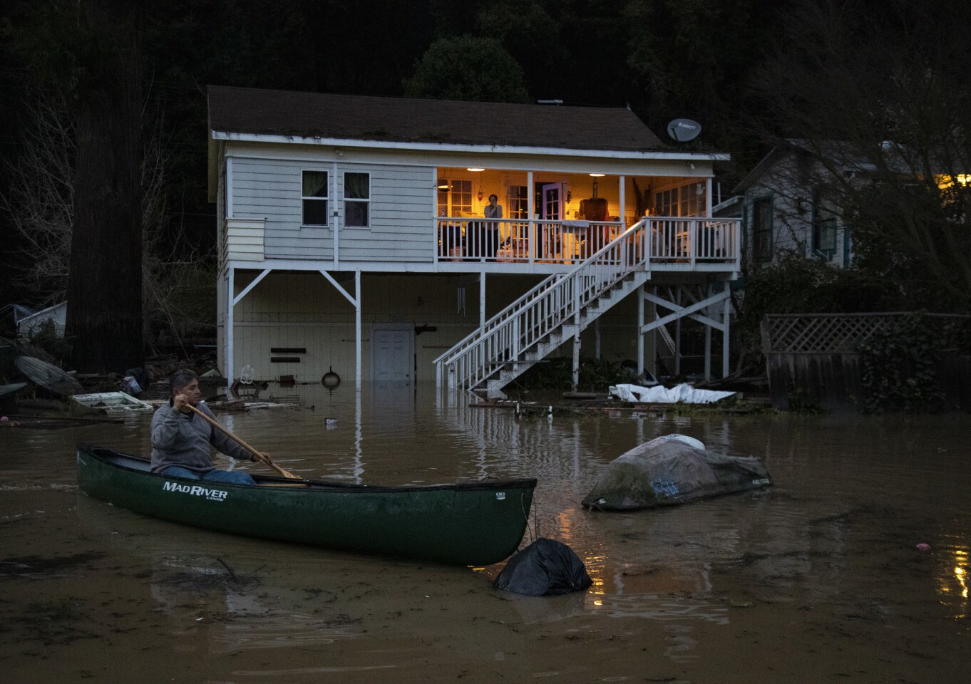 Richard López, de Río Nido, California, usa una canoa para recuperar su moto acuática, que flotaba en las aguas de la inundación frente a su casa en el Russian River Valley.