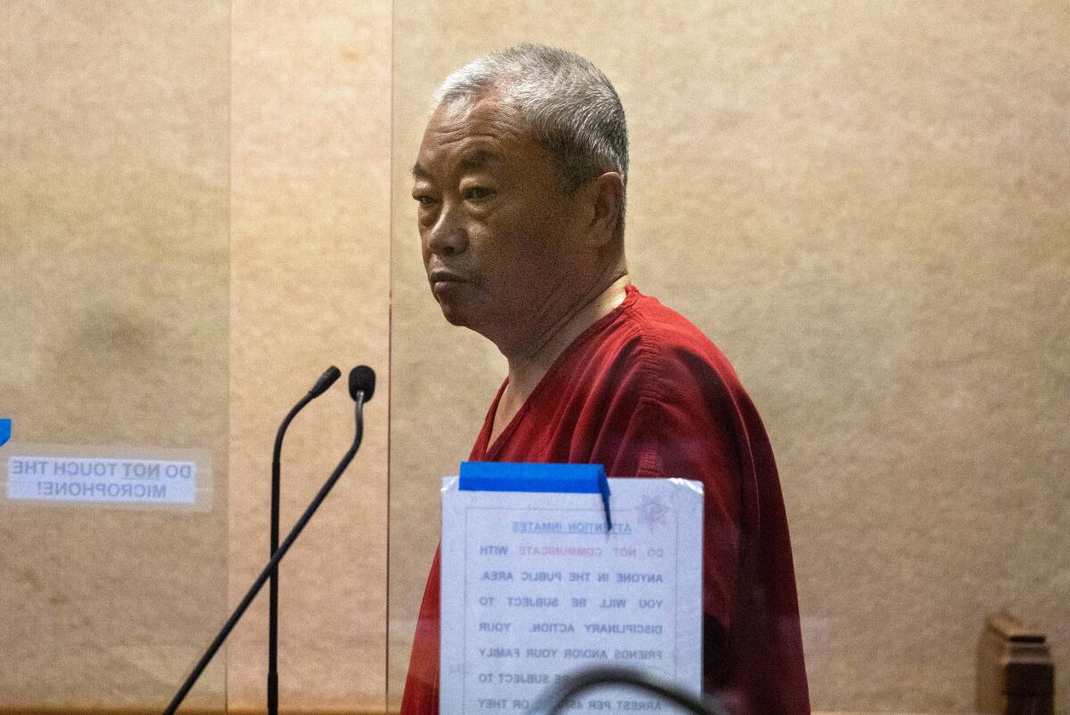 A man is standing behind a see-through partition during an arraignment in San Mateo Superior Court