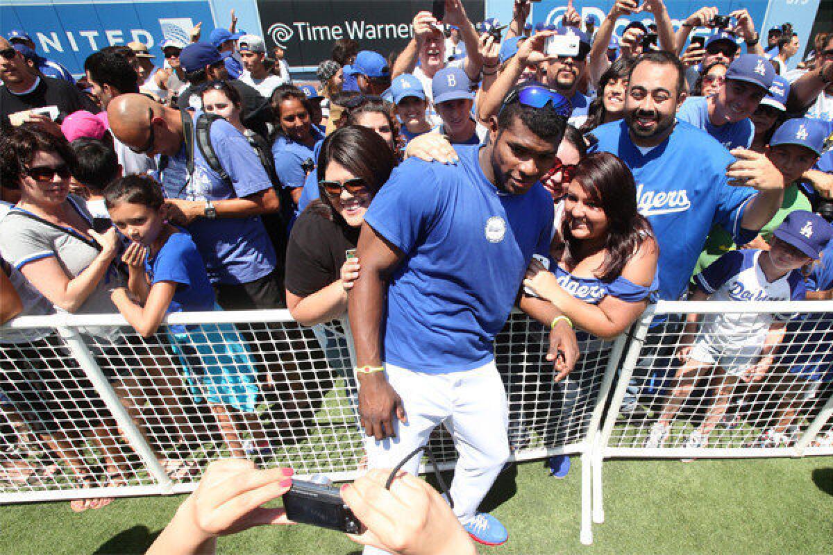 Dodgers star Yasiel Puig didn't play Saturday against Colorado, but he did take the time to pose for photos with fans before the game at Dodger Stadium.
