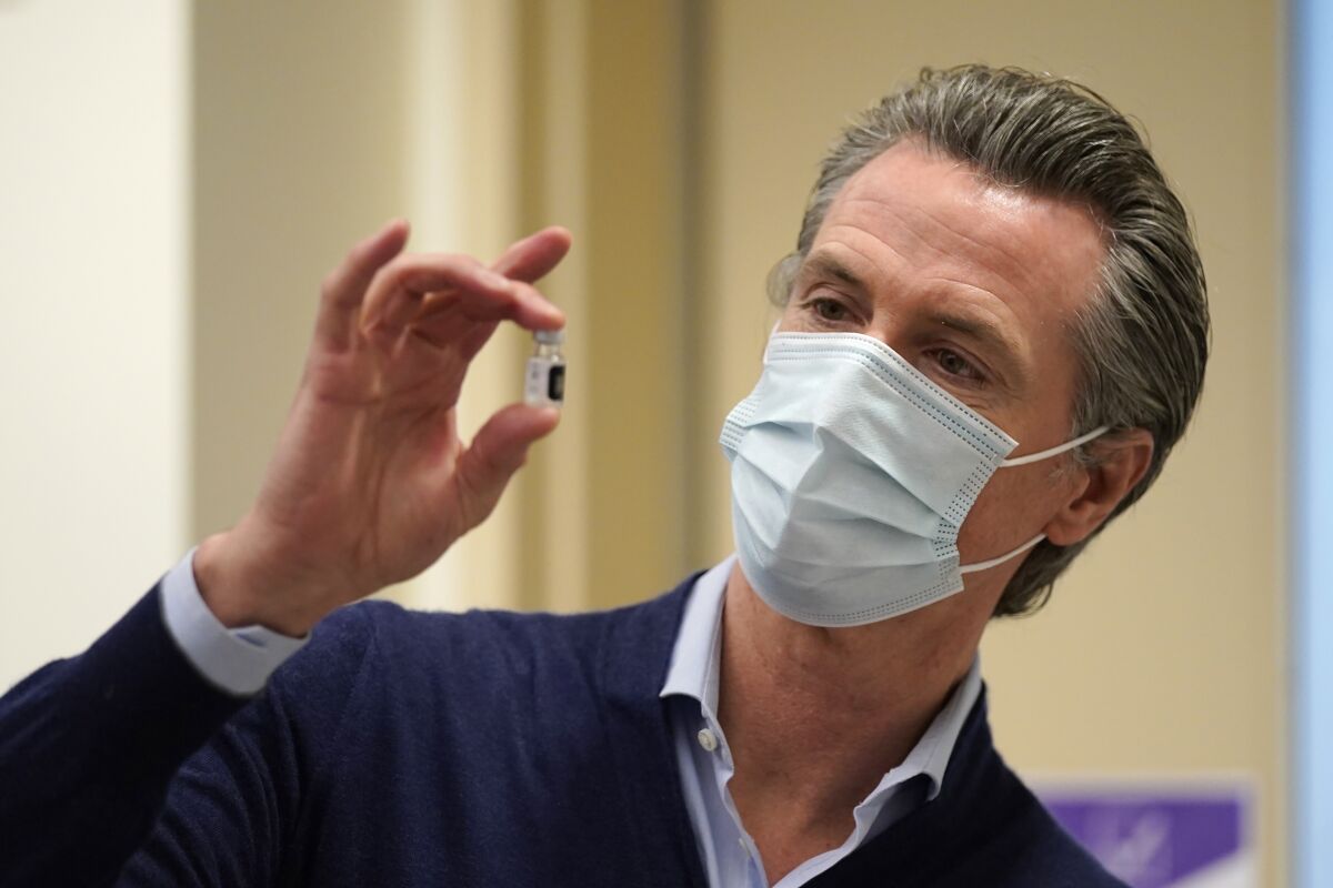 Gov. Gavin Newsom holds a vial of the Pfizer-BioNTech COVID-19 vaccine.