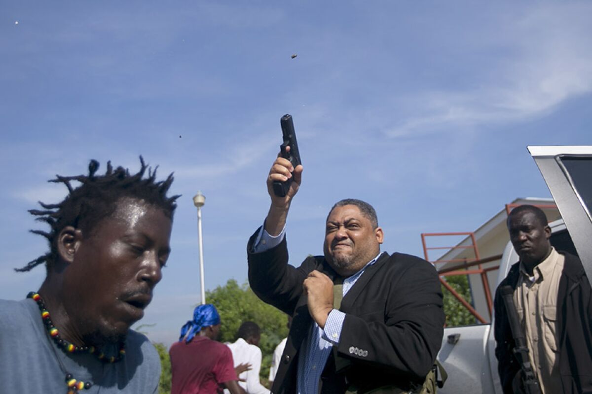 Sen. Ralph Fethiere fires his gun outside Haiti's Senate in Port-au-Prince on Monday. Fethiere, who is from the governing party, pulled a pistol when protesters rushed at him and members of his entourage.