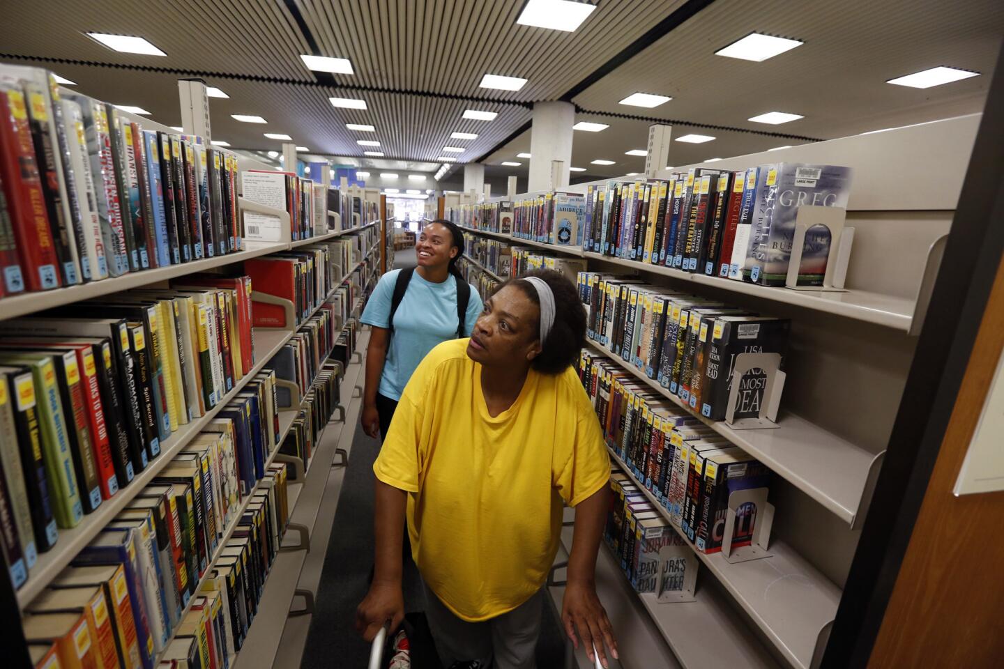Cal State Long Beach student Shellv Candler, 28, in back, helps her mother, Genice Candler-Brown, 60, find mystery books at the Long Beach Public Library in July.