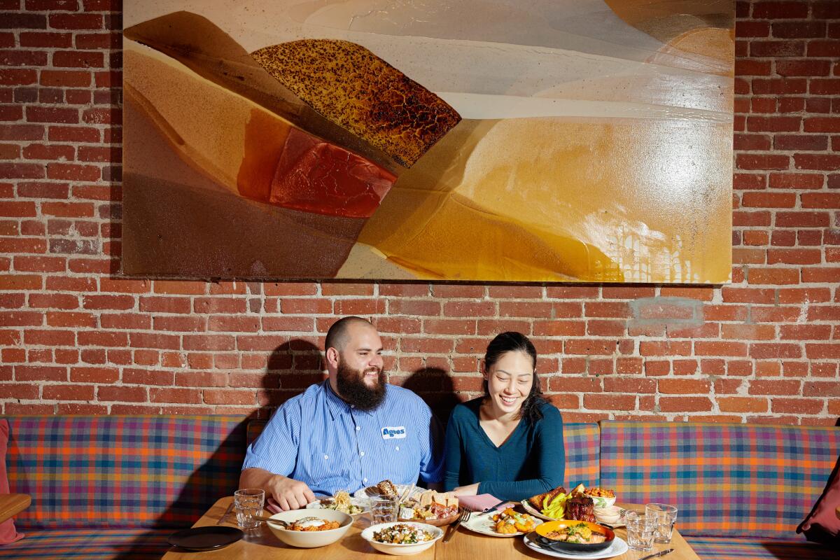 At Agnes in Pasadena, a man and woman sit at a table filled with food. 